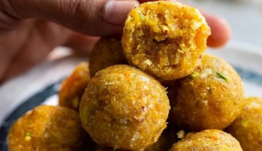Spicy balls of apricots with pistachios and ginger, one of them is bitten and a woman's hand reaches for it.
