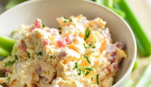 A bowl full of creamy spread with cheese and toasted bacon.