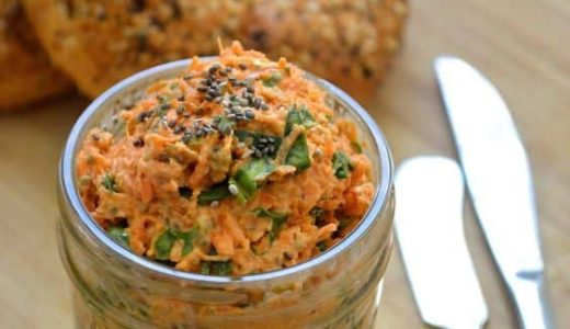 A jar full of cheese and carrot spread ready to be spread.