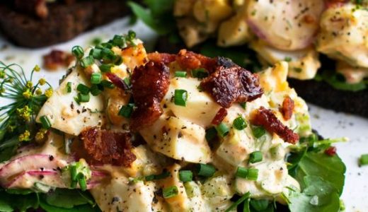 Decorated sandwich with spread, salad and bacon.