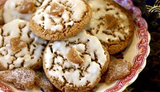 Rye cookies with icing and a piece of candied ginger on a plate.