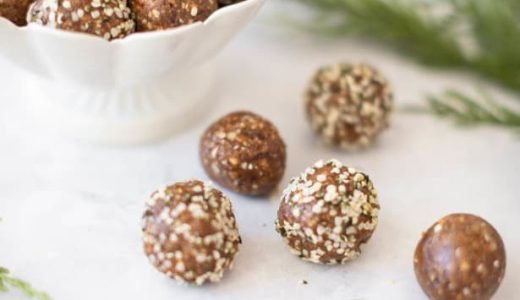 Balls of almonds, oatmeal, hemp seeds, nut butter, dates and gingerbread spice in a bowl. Other balls are placed next to the bowl.