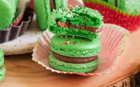 Green macaroons with Christmas sprinkles filled with creamy and rich dark chocolate filling.