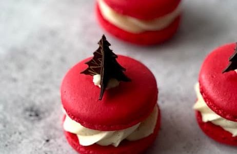 Red macaroons filled with whipped ginger-vanilla ganache and pear jelly and decorated with chocolate.