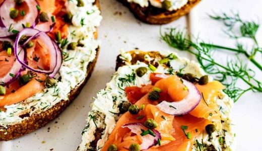 Delicious sandwich with smoked salmon decorated with capers and onions.