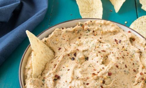 A bowl of creamy spread with chilli flakes on top.