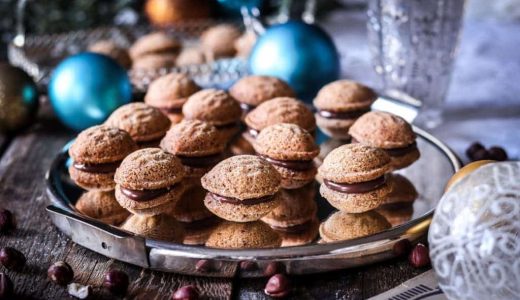 Christmas nuts made of rice flour and hazelnuts filled with hazelnut cream on a tray.