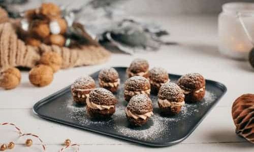 Nuts filled with vanilla pudding cream, milk chocolate and walnut paste on a baking sheet.