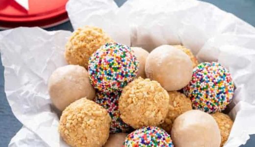 Peanut balls in a bowl lined with baking paper.