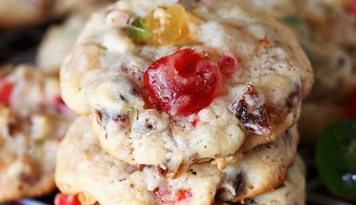 Christmas cookies filled with candied cherries, candied pineapple, pecans and dates stacked on top of each other.