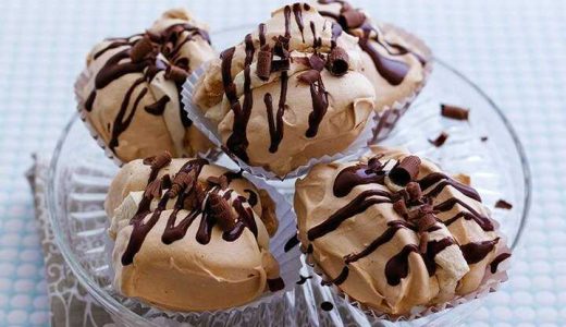 Cane sugar meringues filled with whipped cream with cinnamon and drizzled with melted chocolate on a serving tray.