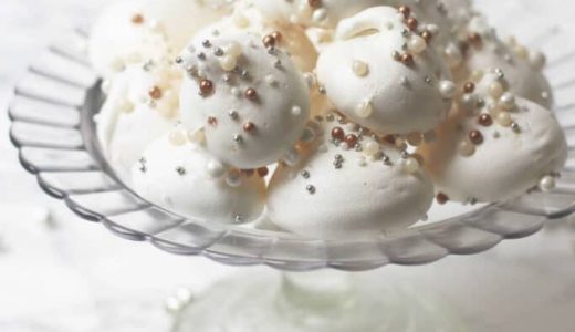 Snow meringues with coconut decorated with pearls and served on a serving tray.