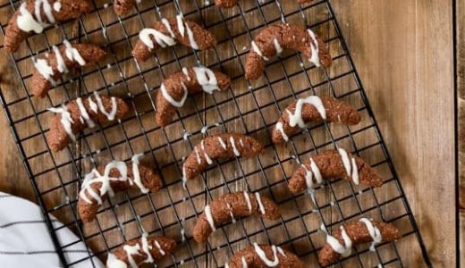 Almond rolls drizzled with glaze placed on a rack.