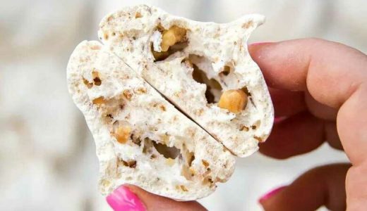 Two hazelnut meringues held by a hand.
