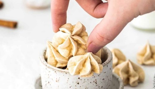 Cinnamon meringues in a bowl, and a hand scooping them up.